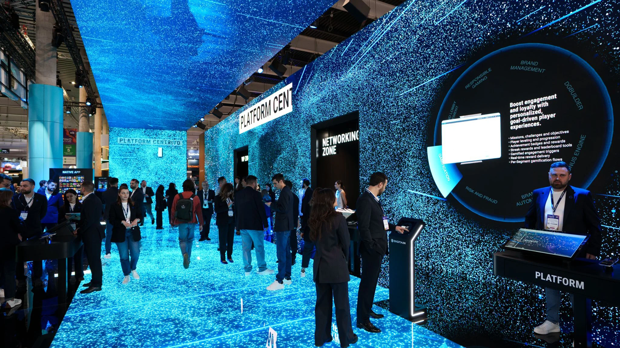 Walkthrough view inside the Digitain stand with immersive blue LED floor and walls, Platform Centrivo signage, and networking area.