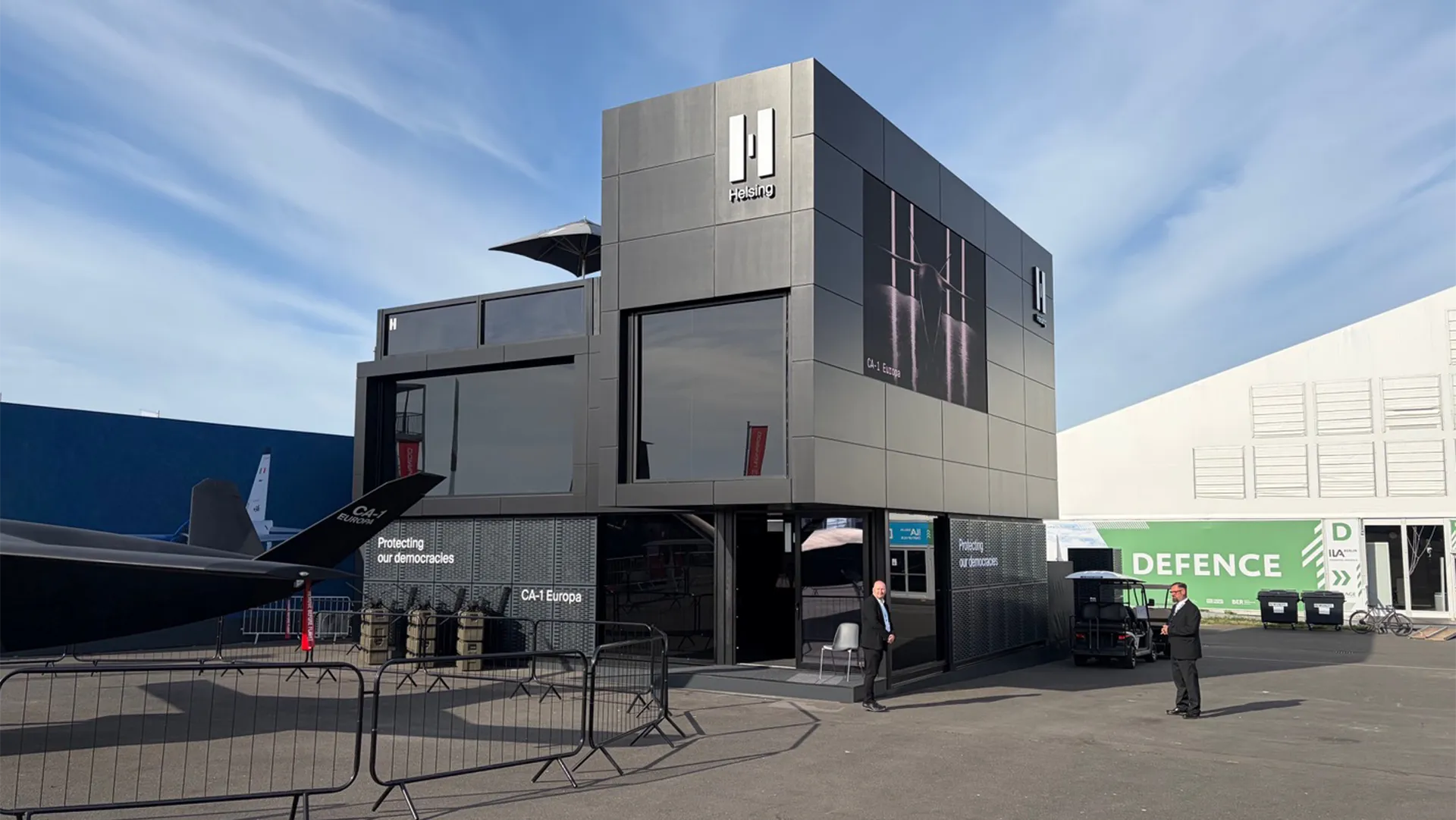 Front entrance and branded façade of Helsing’s chalet at ILA Berlin 2026, with the CA-1 Europa aircraft alongside