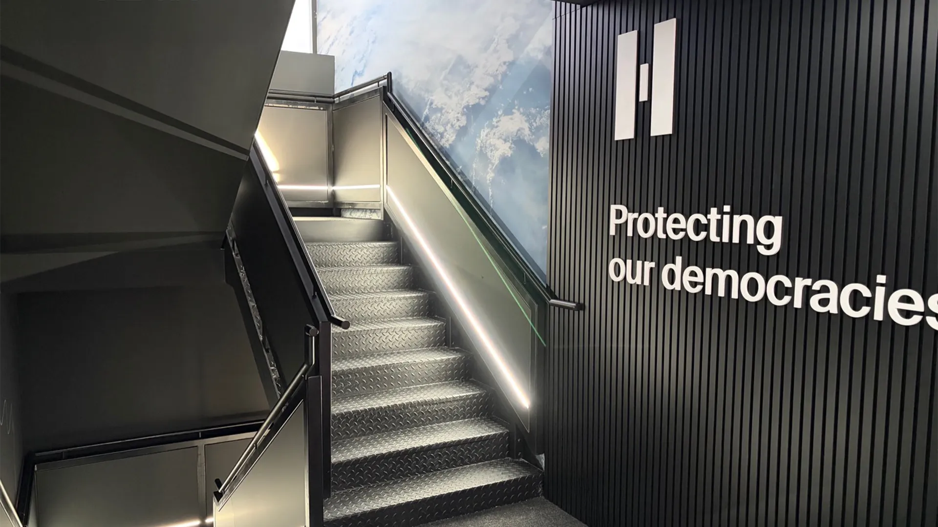 Illuminated staircase inside Helsing’s ILA Berlin chalet beside the words “Protecting our democracies”
