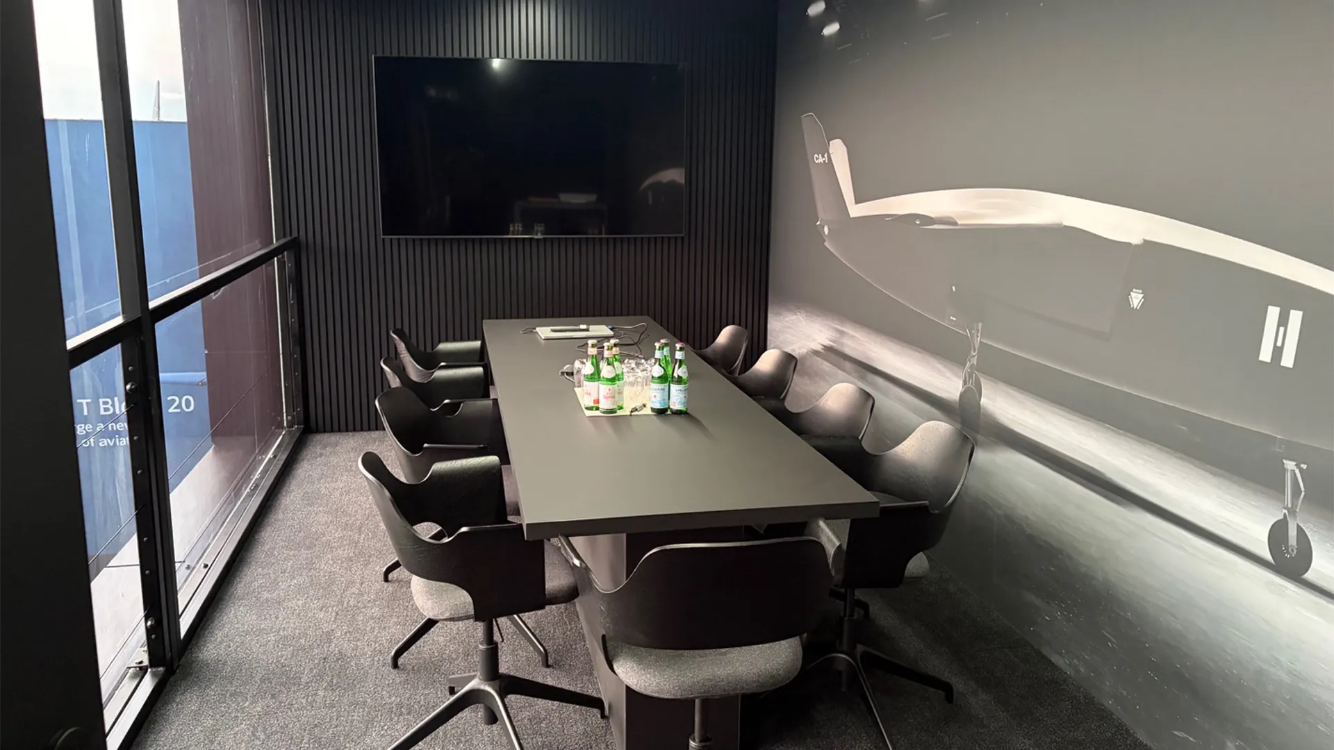 Meeting room inside Helsing’s ILA Berlin chalet with aircraft graphics, presentation screen and conference table